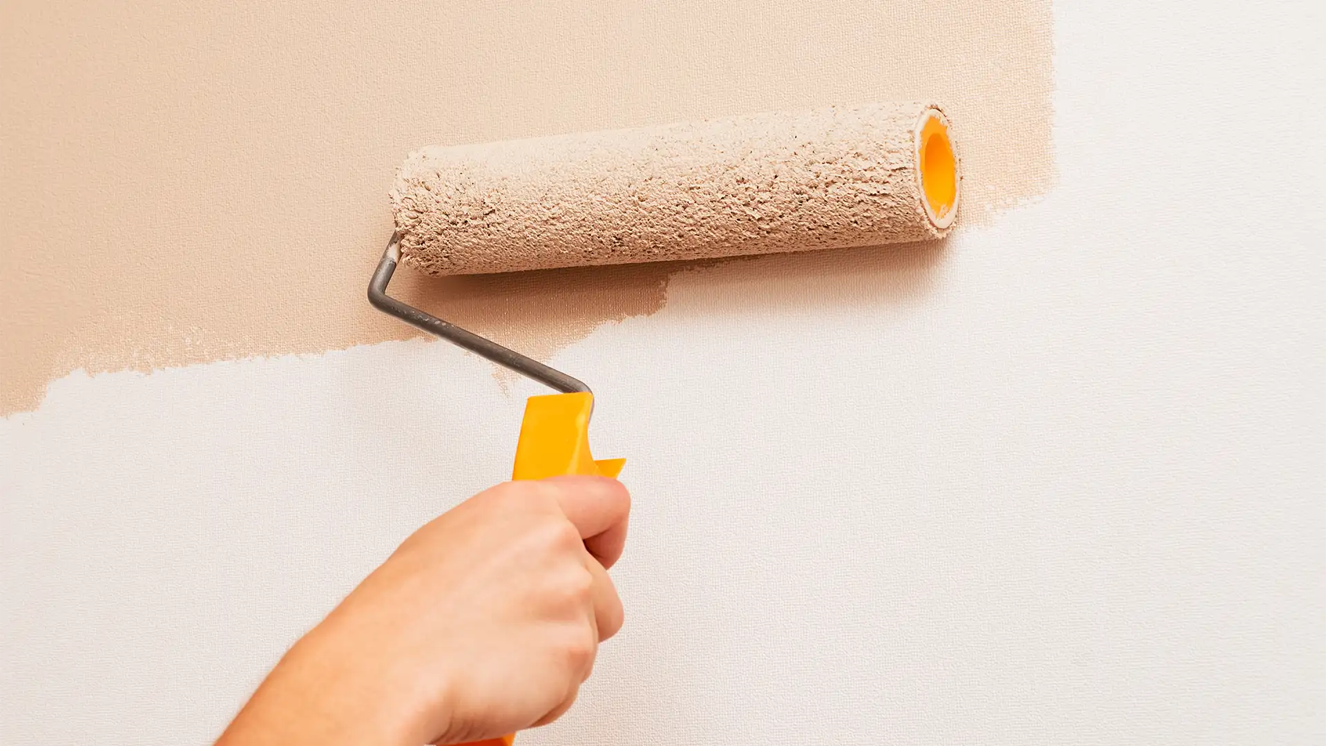 pintura Mano aplicando pintura en una pared interior utilizando un rodillo para renovar el espacio.